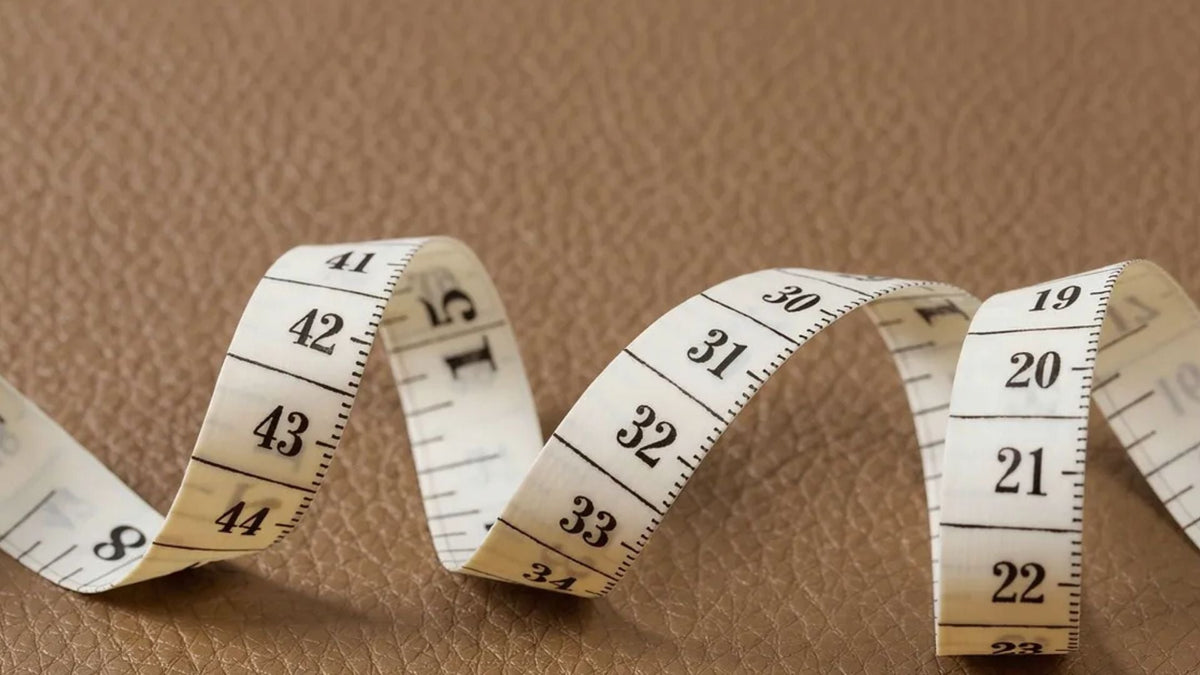 Measuring a hand for glove size with a tape around the knuckles, excluding the thumb